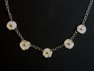 Five small white flowers with gold centres on chain necklace