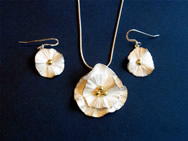 Circular white flower pendant with gold centre; matching earrings