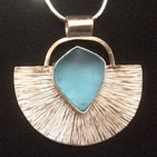 Pendant: inverted semicircle with radiating striations; turquoise glass shape set in centre