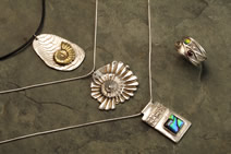 Three pendants: two shell-themed and one with dichroic glass on a silver setting; ring with wave pattern and tiny stones inset