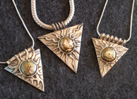 Three small gold inverted triangle pendants with central gold sun with radiating rays