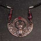 Pendant: scarab beetle holding red stone in circle on semicircular background with geometric patterns; red beads