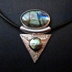 Pendant: oval dichroic glass in silver setting above, silver inverted triangle below with central gold sun and lines radiating outwards